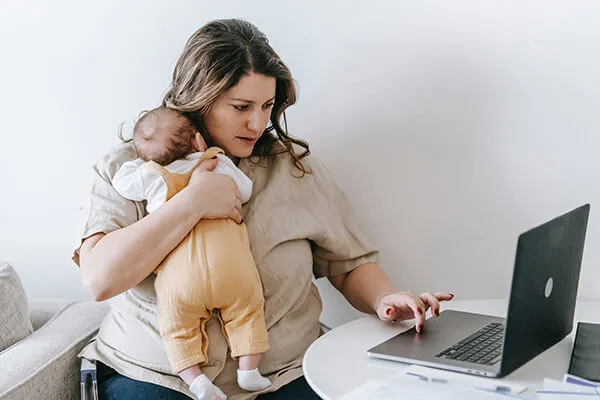 Moeder met baby in de hand voor laptop
