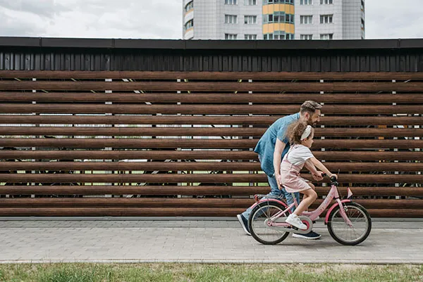 Papa duwt kind op de fiets