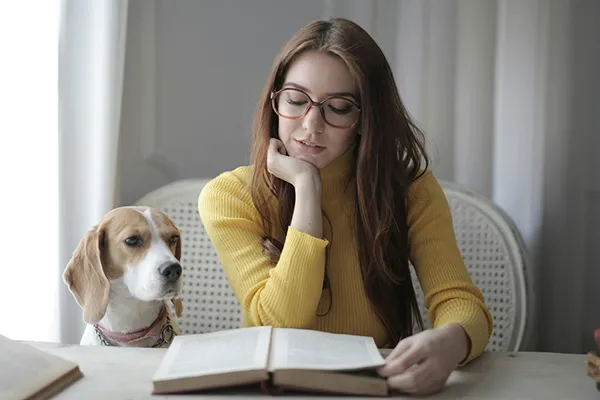 Student leest een cursus tijdens het studeren met haar hond naast haar