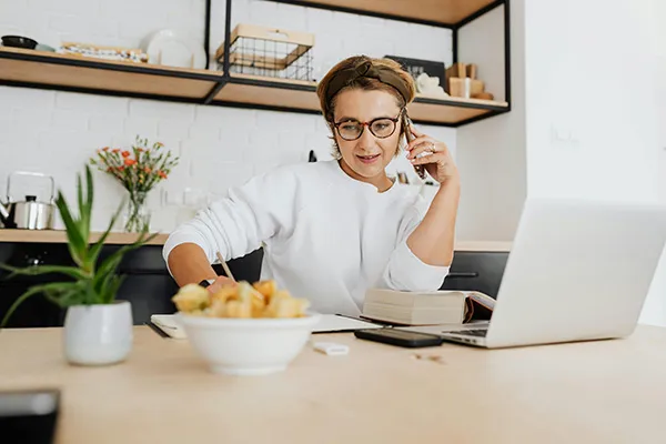 Vrouw aan het bellen met laptop en boeken voor haar