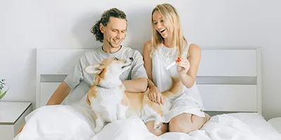 Koppel met zwangerschapstest en hond in bed